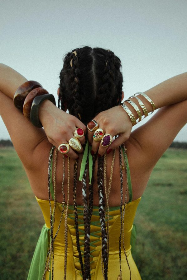 Rear view of a woman in a yellow dress with braided hair adorned with colorful rings and bracelets.