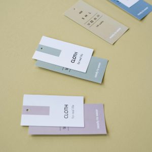 Close-up of minimalist clothing tags placed on a soft yellow surface, showcasing fashion and branding concepts.